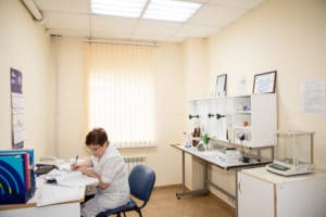 Женщина сотрудник лаборатории сидит за столом